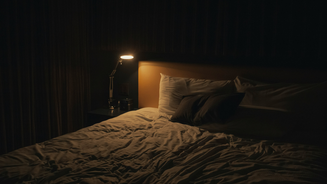 Lit vide la nuit avec lampe de chever allumée